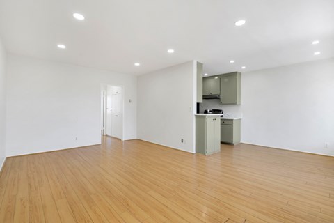 A room with wooden floors and a white wall with a cabinet and mirror.